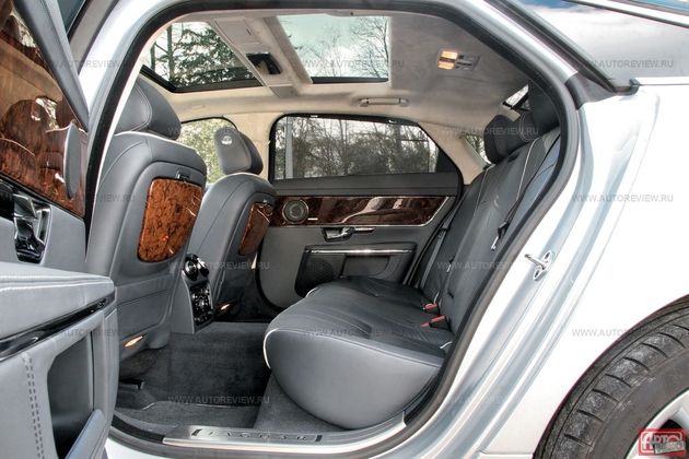 Простор для ног королевский, но вот над головой места немного. Даже у длиннобазного автомобиля (на фото) базовое оснащение очень скромное: стеклянная крыша да деревянные столики (короткобазный XJ обходится без них). В пакете опций Portfolio за 290 тысяч рублей есть передние кресла с электромассажером, четырехзонный климат-контроль плюс подогрев и вентиляция заднего дивана, а добавив 77600 рублей можно заказать мультимедиасистему с семидюймовыми мониторами, интегрированными в подголовники. Но вот задних кресел с массажем и индивидуальными регулировками, равно как и электропривода шторок на боковых окнах, Jaguar пока не предлагает